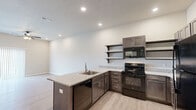 This 1-bedroom, 1-bathroom unit offers a thoughtfully designed layout across a single floor, making efficient use of its space. The open-concept kitchen and living area serves as the heart of the unit, featuring light wood-tone luxury vinyl plank flooring, recessed lighting, and a textured ceiling. The kitchen is well-appointed with dark espresso cabinetry, granite-look countertops, a peninsula with a stainless steel sink, black appliances including a refrigerator, electric range, dishwasher, and microwave, as well as open shelving for added storage and display space. The living area flows naturally from the kitchen, creating a connected and functional common space. The primary bedroom is generously sized, finished with plush carpeting, a ceiling fan with light fixture, and a large window dressed with vertical blinds that allows for ample natural light. It provides direct access to a dedicated closet and the full bathroom. The bathroom is clean and modern, featuring the same wood-tone flooring, a dark vanity with granite-look countertop, a mirror, and a full tub-shower combination. A separate closet adds additional storage convenience. Neutral tones throughout lend the unit a bright, move-in-ready appeal.