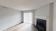 Located at 200 NC-54 E in Carrboro, North Carolina, this single-floor residence offers a well-organized layout with a blend of practical finishes and comfortable living spaces throughout.

The living area serves as the heart of the home, featuring hardwood-style plank flooring, neutral gray walls, and a textured ceiling. A full-width sliding glass door with vertical blinds floods the room with natural light and provides views of the surrounding outdoors. A classic fireplace with a clean white mantel and dark surround anchors one wall, adding a warm focal point to the space.

The galley-style kitchen is efficiently designed with white upper cabinetry and contrasting dark lower cabinets, complemented by light countertops and a stainless steel sink. Stainless steel appliances, including a refrigerator, electric range, and dishwasher, complete the kitchen's functional appeal. The same hardwood-style flooring continues here, maintaining a cohesive look.

The bedrooms are carpeted in a neutral tone, offering a softer underfoot feel. Each bedroom includes a closet, and natural light enters through windows fitted with blinds. The bathroom features a full-size soaking tub and shower combination with chrome fixtures set against clean white surround walls.

Overall, the space presents a clean, move-in-ready aesthetic with consistent neutral tones and updated finishes throughout.