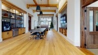 Located at 2500 Gault Way Dr in Summerville, South Carolina, this single-floor community clubhouse blends rustic warmth with modern sophistication throughout its expansive open layout. The entryway makes an immediate impression with soaring ceilings, floor-to-ceiling steel-framed windows, and oversized glass doors that flood the space with natural light while offering clear views of the surrounding community. Warm hardwood flooring runs throughout, complemented by exposed wood ceiling beams that add architectural character and a sense of craftsmanship.

The main gathering area is anchored by a large dark-toned communal table surrounded by sleek black chairs, ideal for group meetings or social events. A built-in brick-accented media wall with open shelving and a mounted flat-screen television serves as a focal point, combining function with design. Pendant lighting adds a refined industrial touch overhead.

A welcoming lounge area near the entrance features cognac leather chairs, a central pedestal table atop a patterned area rug, and curated artwork on crisp white walls. A large wood-framed mirror and console table add an elegant, residential feel. Additional rooms branch off the main hall through richly trimmed wood doorways, offering flexible spaces for various uses. Overall, the clubhouse exudes an inviting, upscale atmosphere rooted in thoughtful design.