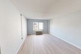 Located at 1850 Post Rd in Warwick, Rhode Island, this one-bedroom, two-bathroom unit offers a thoughtfully organized single-floor layout. The entrance opens into a corridor flanked by a closet, leading into the main living areas. Light wood-style flooring runs throughout, complementing the soft blue-gray wall tones and crisp white trim that define the unit's clean, modern aesthetic.

The living room is an open, well-lit space featuring a wall-mounted HVAC unit and a large window that invites natural light and outdoor views. It flows seamlessly from the entrance, creating a cohesive and airy feel. Adjacent to the living area is the combined dining and kitchen space, equipped with stainless steel appliances including a full-size refrigerator.

The generously sized primary bedroom continues the same light flooring and neutral palette, with a broad window overlooking the surrounding area, providing ample natural light and ventilation via an in-wall HVAC unit.

Both bathrooms are well-appointed with accessible features, including grab bars. One bathroom features a tub/shower with white subway tile surround, while the other includes a lighted vanity mirror, granite-topped floating sink, tiled flooring, and a tub — offering both functionality and a clean, modern finish throughout.