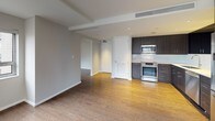 This well-designed 1-bedroom, 1-bathroom residence offers a thoughtful open-concept layout that maximizes both functionality and style. Warm hardwood flooring flows throughout the living and kitchen areas, creating a cohesive and inviting atmosphere.

The living area is bright and airy, anchored by two generously sized windows that frame sweeping city skyline views, filling the space with natural light and an urban energy. The open connection between the living room and kitchen makes the layout feel expansive and ideal for everyday living.

The kitchen is outfitted with dark espresso-toned cabinetry, crisp white quartz countertops, and a clean subway tile backsplash. Stainless steel appliances — including a range, over-the-range microwave, and dishwasher — provide a polished, modern finish. A pass-through design enhances the open feel between the kitchen and living areas.

The bathroom is a standout feature, finished in a clean, minimalist aesthetic with light stone-look tile flooring, a floating vanity with a white countertop, and a frameless glass walk-in shower equipped with both a rainfall ceiling head and a handheld fixture. Recessed lighting completes the spa-like atmosphere.

Overall, this residence combines contemporary design with practical finishes, offering a refined urban living experience.