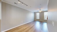 This three-bedroom, two-bathroom multi-floor home in Rockville, Maryland offers a thoughtfully organized layout spread across three levels. The ground floor provides direct access to a private attached garage, offering secure parking and additional storage. The main living level features an open, airy layout with warm hardwood-style flooring, crown molding, and a ceiling fan. Track lighting complements the natural light streaming through multiple windows, while a classic wood-railed staircase adds architectural character. The kitchen is well-equipped with sage-toned cabinetry, dark granite-style countertops, black appliances including a gas range, microwave, dishwasher, and refrigerator, plus a large window that fills the space with natural light. A louvered-door closet provides convenient pantry storage. The upper floor hosts all three bedrooms, including a generously sized primary bedroom, along with a hallway and two full bathrooms. The bedrooms feature plush carpet, ample closet space with paneled double doors, and bright windows. Both bathrooms are finished with light cabinetry, white tile tub-shower combinations, and vanity lighting. Crown molding and neutral tones carry throughout, creating a clean, cohesive aesthetic.