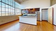 Located at 675 North Main Street in downtown Winston-Salem, this one-bedroom, two-bathroom loft showcases an industrial-chic aesthetic with soaring ceilings, exposed ductwork, and warm bamboo hardwood flooring throughout. The open living area is bathed in natural light from oversized factory-style windows offering urban views. The kitchen features rich dark wood cabinetry, granite countertops, stainless steel appliances, and a breakfast bar island. The spacious bedroom includes two closets for ample storage. Two full bathrooms offer tile flooring and granite accents, one with a tub/shower combo. An in-unit stacked washer and dryer adds everyday convenience.