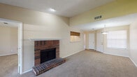 Located at 1510 Dublin Blvd in Colorado Springs, Colorado, this single-floor home offers a well-designed layout with a variety of comfortable living spaces. The living room serves as the centerpiece of the home, boasting soaring vaulted ceilings that lend an open and airy feel. A classic brick fireplace with a raised hearth and white mantel anchors the room, providing both a functional and aesthetic focal point. Soft carpeting and neutral wall tones create a warm, inviting atmosphere throughout. Natural light filters in through front-facing windows near the entryway, which features a pendant light fixture overhead. A convenient pass-through window connects the living area to the kitchen, which is equipped with wood cabinetry and hardwood-style flooring. The bedrooms are generously sized, each featuring plush carpeting, ceiling fan and light fixtures, and textured ceilings. The bathroom is well-appointed with a full tub and shower combination featuring white tile surround, a wood-toned vanity with a single-basin sink, and hardwood-style flooring. Throughout the home, a cohesive neutral palette and functional design elements come together to create a practical and comfortable living environment.