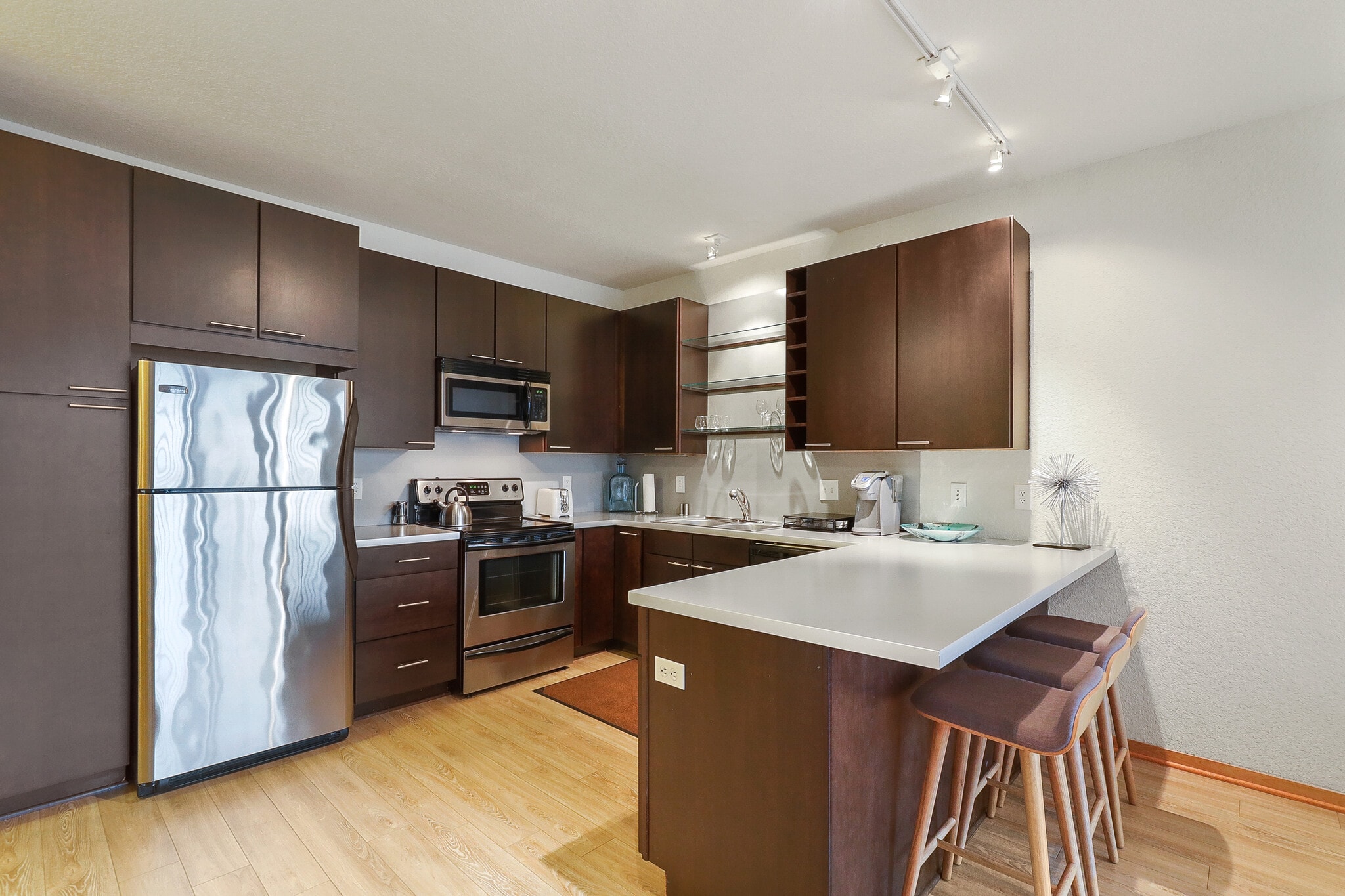 Modern kitchen with stainless steel appliances and dark brown cabinetry.