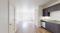 Located at 470 Alexander Loop in Eugene, Oregon, this one-bedroom, one-bathroom residence offers a thoughtfully designed single-floor layout that maximizes functionality and comfort. The open-concept living and kitchen area features warm luxury vinyl plank flooring throughout, creating a bright and cohesive feel. The kitchen is equipped with sleek dark cabinetry, stainless steel appliances including a refrigerator, range, microwave, and dishwasher, along with a built-in sink and ample counter space. The layout flows naturally from the kitchen into the living area, offering a spacious and airy atmosphere. The bedroom is carpeted for comfort and includes a sliding door closet for storage, as well as convenient in-unit washer and dryer access through a dedicated utility area. A sliding glass door opens directly onto a private balcony surrounded by mature trees, filling the space with natural light and greenery. The bathroom features hardwood-style flooring, a dark wood vanity with countertop, and clean white walls with chrome fixtures. A connecting hallway ties all rooms together efficiently. This residence combines modern design elements with practical living features in a serene Eugene setting.