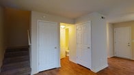 This two-floor residence offers a straightforward and functional layout designed for comfortable everyday living. The interior is finished with warm hardwood flooring that runs throughout, adding a sense of warmth and continuity to the space. Classic six-panel white doors are featured prominently, lending a clean, traditional aesthetic to the home's interior design. The ceiling height provides a comfortable sense of volume in each room, while neutral wall tones create a versatile backdrop suitable for a variety of interior styles. A full bathroom is conveniently accessible from the adjoining room, complete with standard fixtures and warm interior lighting. The practical placement of doors and rooms reflects a thoughtful approach to traffic flow and accessibility within the home. Ventilation is supported by ceiling vents visible throughout, ensuring year-round climate comfort. The overall ambiance of the space is understated and clean, with a focus on functionality and ease of use. Spread across two floors, the home offers well-defined living areas that provide both shared and private spaces, making it well-suited for a range of occupants and lifestyles.