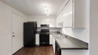 Located at 6851 Sharon Ct in Columbus, Ohio, this multi-story residence spans three floors, offering generous living space distributed across a well-organized layout. The kitchen is a standout feature, showcasing an abundance of white cabinetry that extends to the ceiling for maximum storage. Dark granite-style countertops provide a striking contrast against the bright cabinetry, while a full suite of black appliances — including a refrigerator, electric range with overhead vent, and dishwasher — gives the kitchen a cohesive, practical aesthetic. A double-basin stainless steel sink is positioned beneath convenient counter space, and rich hardwood-style flooring grounds the room with warmth. Track lighting illuminates the kitchen from above, and a textured ceiling adds architectural character. The multi-floor design of this home provides distinct separation between living areas, allowing for versatile use of space throughout. The clean, neutral color palette across the interior creates a bright and welcoming ambiance, making it an adaptable environment suited to a variety of lifestyles. With its functional layout and well-appointed kitchen, this Columbus residence offers a comfortable and practical living experience across all three levels.