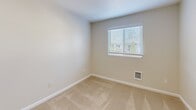 Located in Edmonds, WA, this well-designed 2-bedroom, 1-bathroom residence offers a practical and comfortable single-floor layout. The kitchen is equipped with warm-toned wood cabinetry, granite-look countertops, and black appliances including an electric range and built-in microwave. A textured accent wall adds character to the cooking space, which opens toward the main living area via a half-wall peninsula. Wood-style plank flooring flows throughout the main living and hallway areas, creating a cohesive and easy-to-maintain aesthetic. A central hallway connects the key rooms of the home, with flush ceiling lighting providing consistent illumination throughout. Both bedrooms feature plush neutral carpeting and windows fitted with horizontal blinds that allow for natural light and privacy control. The primary bedroom includes a sliding-door closet, while the second bedroom offers its own closet with wire shelving for organized storage. A wall-mounted heating unit is present in each bedroom for individualized climate comfort. The shared bathroom is clean and functional, featuring a full tub-shower combination with chrome fixtures. The overall palette of soft neutrals, white trim, and consistent finishes lends the space a bright, move-in-ready feel suited for a variety of living arrangements.