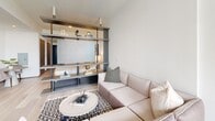 Located on the 12th floor at 915 Division St in Nashville's vibrant Gulch neighborhood, this 410-square-foot studio apartment delivers a refined urban living experience within a thoughtfully designed single-level layout. The open-concept living area is anchored by floor-to-ceiling sliding glass doors that flood the space with natural light and provide direct access to a private balcony offering expansive city skyline views. Light hardwood-style flooring runs throughout, complementing the clean, neutral color palette. A modern open-shelf room divider elegantly defines the sleeping area from the living space, adding architectural interest while maintaining an airy feel. The kitchen is outfitted with stainless steel appliances, including a Frigidaire electric range with a built-in microwave above, paired with sleek dark cabinetry, white quartz countertops, a classic subway tile backsplash, and a matte black undermount sink. The bathroom features large-format neutral tile walls and flooring, a walk-in glass-panel shower with hexagonal mosaic floor tiles, and matte black fixtures throughout. A hallway connects all areas seamlessly, optimizing the efficient use of the studio's 410 square feet of total floor area.