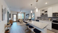 This well-appointed single-floor residence offers a thoughtfully designed open-concept layout that seamlessly connects the kitchen, dining, and living areas. The kitchen is a standout feature, showcasing crisp white shaker cabinetry, granite countertops, a herringbone tile backsplash, stainless steel appliances, and a generously sized island with seating — ideal for casual dining and entertaining. Pendant lighting above the island adds a refined touch.

The living area is bright and welcoming, benefiting from large windows and a glass door that open to a private balcony, filling the space with natural light and offering pleasant outdoor views. A ceiling fan overhead adds both style and comfort.

Two well-sized bedrooms provide restful retreats. The primary bedroom features broad windows with outdoor views, plush carpeting, and access to a spacious walk-in closet with multi-tier wire shelving. A second bedroom offers a cozy atmosphere with a distinctive accent wall. The bathroom is finished with marble-style tile surrounds on the soaking tub, a granite vanity, and light tile flooring. Throughout the common areas, durable wood-look flooring ties the interior together, creating a cohesive, modern aesthetic.