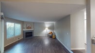 Unit 14D is a thoughtfully designed single-floor residence that balances comfort and functionality throughout its layout. The spacious living room serves as the heart of the home, showcasing rich, dark hardwood-style flooring and a classic fireplace with a white mantle, creating a warm and inviting focal point. Large windows and a sliding glass door flood the space with natural light while providing direct access to a private outdoor area with views of surrounding greenery.

The kitchen is designed for both practicality and social interaction, featuring white cabinetry, stainless steel appliances including a range, microwave, and refrigerator, and a generous peninsula countertop with bar seating for two. An adjacent dining area with lighter hardwood-style flooring and a ceiling fan offers a seamless transition between cooking and living spaces.

The bedrooms are carpeted for comfort and include ceiling fans and windows that bring in natural light. The bathrooms are clean and functional, with one featuring a full tub-shower combination, white cabinetry with grey countertops, and brushed nickel fixtures, while a second bathroom provides a shower with curtain and matching hardware. Neutral grey tones throughout create a cohesive, modern ambiance.