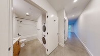 Located at 104 12th Ave in Seattle's vibrant Capitol Hill neighborhood, this modern one-bedroom, one-bathroom unit offers a thoughtfully designed layout with contemporary finishes throughout. Polished concrete floors flow seamlessly across the entire space, lending an industrial-chic aesthetic that complements the clean white walls and recessed lighting.

The open living and kitchen area is a standout, featuring warm wood cabinetry, a classic white subway tile backsplash, stainless steel appliances — including a refrigerator, range, microwave, and dishwasher — and a deep sink. Large windows flood the living area with natural light and frame views of the surrounding cityscape, creating an airy, open ambiance.

The bedroom is a comfortable retreat with its own large window overlooking the city, a ceiling fan, and access to a dedicated closet fitted with built-in shelving and outfitted with a stylish sliding barn door with matte black hardware. The full bathroom is clean and functional, featuring a soaking tub, shower, vanity with wood cabinetry, and a stacked washer and dryer conveniently tucked behind a door in the hallway just outside. The hallways connect all spaces efficiently, completing this well-appointed urban home.
