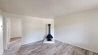 Located at 2112 Moon St NE in Albuquerque, New Mexico, this efficient one-bedroom, one-bathroom residence offers a well-considered layout across a single floor. Light-toned, wood-look flooring runs throughout the space, creating a cohesive and clean aesthetic from room to room.

The living room serves as the heart of the home, highlighted by a striking freestanding wood-burning stove set on a tiled hearth — a distinctive architectural feature that adds warmth and character. A large window allows natural light to fill the room, while a textured ceiling adds subtle visual depth.

The kitchen is thoughtfully designed in a U-shaped configuration, featuring white cabinetry, white tile backsplash, laminate countertops, and a full suite of white appliances including a gas range and refrigerator. A window provides natural light and an outdoor view, making the space feel open despite its compact footprint.

The bedroom is a comfortable, well-proportioned retreat with a window overlooking greenery and direct access to a dedicated walk-in closet, offering practical storage. The full bathroom is clean and functional, complete with a shower-tub combination and a vanity with storage.

Overall, the space presents a practical and comfortable living environment with thoughtful details throughout.