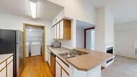 Located in Comstock Park, Michigan, this well-appointed two-bedroom, two-bathroom home offers a practical and comfortable single-floor layout. The kitchen is outfitted with wood-trimmed cabinetry, a stainless steel refrigerator, dishwasher, and microwave, complemented by a convenient peninsula with countertop seating. An adjacent laundry room with a full-size washer and dryer adds everyday convenience. Warm hardwood-style flooring runs through the kitchen and utility areas, while plush carpeting extends throughout the living room and bedrooms. The living room is bright and airy, featuring a ceiling fan, a fireplace, and a sliding glass door that opens to a private balcony with outdoor views. The generously sized primary bedroom offers ample natural light and includes a closet, with access to a full en-suite bathroom featuring a walk-in glass shower, a wide vanity with under-sink storage, and a large mirror. The second bedroom is well-proportioned with a window and a dedicated closet. The second bathroom includes a tub-shower combo, a single-sink vanity with storage drawers, and light hardwood-style flooring. A connecting hallway ties the layout together, making this home both functional and inviting.