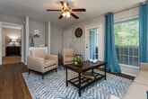Located at 20 Mason Dr in Red Bank, Tennessee, this single-floor residence offers a well-designed layout that balances comfort and functionality. The open-concept living area is anchored by rich hardwood flooring, a ceiling fan with light fixture, and large windows dressed with teal drapes that allow generous natural light. A private exterior door provides direct outdoor access from the living room. The space flows seamlessly into a dining area and kitchen, which features white cabinetry, granite countertops, a classic subway tile backsplash, black appliances including an electric range and over-the-range microwave, and a pass-through counter that connects to the dining space. Both bedrooms are carpeted and equipped with ceiling fans, offering a comfortable retreat. Each room includes window treatments and ample closet space, with the primary bedroom featuring a walk-in closet. The two bathrooms are finished with granite vanity tops, white cabinetry, and large mirrors. A dedicated in-unit laundry room with built-in shelving adds everyday convenience. Throughout the residence, neutral tones and consistent finishes create a cohesive and inviting atmosphere.
