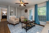 Located at 20 Mason Dr in Red Bank, Tennessee, this single-floor residence offers a well-designed layout that balances comfort and functionality. The open-concept living area is anchored by rich hardwood flooring, a ceiling fan with light fixture, and large windows dressed with teal drapes that allow generous natural light. A private exterior door provides direct outdoor access from the living room. The space flows seamlessly into a dining area and kitchen, which features white cabinetry, granite countertops, a classic subway tile backsplash, black appliances including an electric range and over-the-range microwave, and a pass-through counter that connects to the dining space. Both bedrooms are carpeted and equipped with ceiling fans, offering a comfortable retreat. Each room includes window treatments and ample closet space, with the primary bedroom featuring a walk-in closet. The two bathrooms are finished with granite vanity tops, white cabinetry, and large mirrors. A dedicated in-unit laundry room with built-in shelving adds everyday convenience. Throughout the residence, neutral tones and consistent finishes create a cohesive and inviting atmosphere.