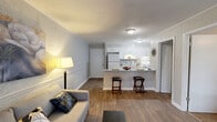 Located at 2360 W Broad St in Athens, GA, this well-appointed 1-bedroom, 2-bathroom single-floor unit offers a thoughtfully designed layout that maximizes its compact footprint. The open-concept living and kitchen area serves as the heart of the space, featuring warm hardwood-style flooring, crown molding, and textured accent walls that add visual depth. The living room is bright and welcoming, with a large sliding glass door fitted with vertical blinds that allows generous natural light to fill the room.

The kitchen is efficiently designed in a galley-style configuration, complete with white cabinetry, a mosaic tile backsplash, white appliances, and a peninsula breakfast bar with bar stool seating — ideal for casual dining. A pass-through view connects the kitchen seamlessly to the living area, enhancing the open feel.

The bedroom is a comfortable retreat, carpeted for warmth, and features a ceiling fan, crown molding, and windows that bring in natural outdoor views. Two full bathrooms serve the unit, each including a shower-tub combination. A dedicated closet provides additional storage. The overall ambiance is clean, neutral, and functional — well-suited for comfortable everyday living in a convenient Athens location.