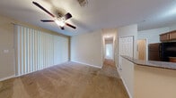 Located at 5819 Legacy Crescent Pl in Riverview, FL, this single-floor residence offers a functional and comfortable layout designed for everyday living. The living area serves as the heart of the home, featuring warm beige carpeting, a ceiling fan with light fixture, and large vertical-blind-covered sliding doors that invite abundant natural light and provide views of the surrounding greenery. Built-in corner shelving adds a practical decorative touch near the entryway. A central hallway connects the living spaces to the private bedrooms, each finished with soft carpeting, ceiling fans, and windows overlooking the outdoors. The bedrooms offer well-proportioned spaces with clean lines and neutral wall tones. The kitchen is well-appointed with warm wood cabinetry, dark granite-style countertops, a classic tile backsplash, tile flooring, and black appliances including a range, microwave, and dishwasher. The bathroom features a tub-shower combination, a wood vanity with granite countertop, overhead storage cabinetry, and tile flooring. Throughout the home, neutral tones, consistent finishes, and practical design elements contribute to a cohesive and move-in-ready living environment.