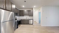 Located in Middleburg, Florida, this well-appointed single-floor residence offers a thoughtfully designed layout encompassing one bedroom, one bathroom, and two closets. The open-concept kitchen and living area serves as the heart of the home, where light wood-style flooring flows seamlessly throughout. The kitchen is outfitted with a full suite of stainless steel appliances — including a refrigerator, electric range, microwave, and dishwasher — complemented by dark wood-toned cabinetry, granite-look countertops, and a classic white tile backsplash. Recessed lighting adds a clean, modern feel to the space. The living area is bright and open, with natural light filtering in through windows fitted with blinds, and a ceiling fan overhead. The bedroom features plush carpeting, a ceiling fan, and a window offering outdoor views, creating a comfortable and restful retreat. Two closets provide ample storage throughout. The bathroom is finished with a granite-topped vanity, dark cabinetry with brushed nickel hardware, a tiled tub-shower combination, and light wood-style tile flooring. Neutral tones and modern finishes throughout lend the space a clean, contemporary ambiance.