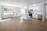 Located at 2293 Eglinton Ave E in Toronto, this 2-bedroom, 1-bathroom unit offers a thoughtfully updated interior with a clean, modern aesthetic. Light-toned hardwood flooring runs throughout, complementing the bright, neutral palette found in every room.

The open kitchen is a standout feature, showcasing white shaker-style cabinetry, white subway tile backsplash, quartz countertops, and a full suite of stainless steel appliances including a refrigerator, electric range, over-the-range microwave, and dishwasher. A peninsula counter connects the kitchen to the living area, creating an open and functional layout. Large windows in the living space allow natural light to fill the room, with baseboard heating and a wall-mounted AC unit providing year-round comfort.

The primary bedroom is generously proportioned, featuring a large window with an urban view and a classic white radiator. The second bedroom also benefits from good natural light and includes access to closet space. Both rooms feature the same consistent light flooring and neutral tones.

The bathroom is cleanly finished with white subway tile surrounding the tub/shower combo, a modern floating vanity with an undermount sink, and a mirrored medicine cabinet. The overall design is cohesive, practical, and move-in ready.