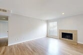 This well-appointed two-bedroom, two-bathroom single-story home in Dallas, Texas offers a thoughtfully designed layout across a comfortable footprint. The bright living room serves as the heart of the home, featuring light hardwood-style flooring, crown molding, recessed lighting, and a tile-surround wood-burning fireplace framed by a window that invites natural light into the space. The open dining and kitchen area flows seamlessly from the living room, showcasing white cabinetry, light countertops, a stainless steel sink, and black appliances including an electric range and dishwasher, complemented by a window above for added brightness. Both bedrooms are carpeted and generously sized, with the primary bedroom offering ample room for furnishings. Closet storage is plentiful throughout, with four closets including walk-in options featuring built-in shelving and hanging rods. The bathrooms are clean and classic, with one featuring a full soaking tub surrounded by white subway tile. Additional conveniences include a dedicated laundry area, a pantry, and a hallway connecting all spaces efficiently. The home's neutral palette and consistent finishes throughout create a cohesive, move-in-ready atmosphere.