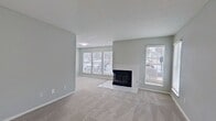 This contemporary apartment offers a blend of style and functionality. The kitchen boasts white cabinetry, stainless steel appliances, and a subway tile backsplash. Bathrooms are elegantly updated with modern fixtures and vanities. The living area features carpeting and large windows for natural light. In-unit laundry adds convenience. Outside, the property is nestled among trees, providing a serene environment. Ample parking is available for residents. The overall design emphasizes clean lines and a neutral color palette, creating a fresh and inviting living space.