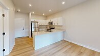 Located at 8484 Brougham Dr in Sterling Heights, MI, this thoughtfully designed one-bedroom, one-bathroom unit offers a clean, modern aesthetic throughout its single floor. Light wood-tone flooring runs continuously across all rooms, complemented by neutral warm-beige walls and crisp white trim, creating a cohesive and bright atmosphere.

The kitchen is a standout feature, equipped with white shaker-style cabinetry, light quartz countertops, a peninsula with an integrated sink and matte black fixtures, and a full suite of stainless steel appliances including a refrigerator, electric range, and built-in microwave. Recessed lighting illuminates the space efficiently.

The bedroom is a well-proportioned, sunlit room featuring a window with blinds that invites natural light, along with a dedicated closet for storage. The bathroom maintains the unit's clean design language with white cabinetry, a white vanity top, and matte black hardware accents, all set on the same warm wood flooring.

A dedicated laundry room provides added convenience, housing a stacked washer and dryer unit alongside a water heater and built-in wire shelving for extra storage. Every room reflects a fresh, move-in-ready condition with consistent modern finishes throughout.