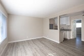 Located at 1495 Peterson Ave in Long Beach, CA, this one-bedroom, one-bathroom unit offers a thoughtfully designed single-floor layout. Light wood-style flooring runs throughout the entire space, lending a clean, cohesive aesthetic to every room.

The living room is generously proportioned, featuring a ceiling fan, a wall-mounted heater, and abundant natural light streaming through large windows fitted with horizontal blinds. The space flows seamlessly into the combined dining room and kitchen area, which is separated by a partial wall with a pass-through window.

The kitchen is well-appointed with white shaker-style cabinetry featuring brushed nickel hardware, dark gray countertops, a deep double-basin stainless steel sink, a gas range, and a full-size refrigerator — all finished in stainless steel.

The bedroom offers a comfortable retreat with a ceiling fan, a large window for natural light, and a mirrored sliding-door closet that adds depth to the room. An additional closet provides further storage convenience.

The bathroom is clean and functional, featuring a tub/shower combo with white tile surround, a window above for ventilation and light, a white vanity with a framed mirror, and brushed nickel fixtures. The neutral tones throughout create a bright, welcoming atmosphere.