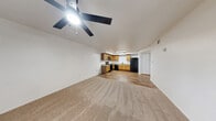 This one-bedroom, one-bathroom unit at 3250 S Town Center Dr in Las Vegas, NV offers a well-organized single-floor layout. The open-concept living, dining, and kitchen area forms the heart of the home, with neutral carpet in the living space transitioning to warm wood-look flooring in the kitchen. A ceiling fan overhead adds comfort to the living area, which also features a window allowing natural light to filter in. The kitchen is well-appointed with warm-toned wood cabinetry, granite-style countertops, and a full suite of black appliances including a range, over-the-range microwave, dishwasher, and refrigerator, all complemented by a deep sink and ample cabinet storage. The spacious bedroom offers plush carpet, a ceiling fan with light, and a window dressed with blinds. It connects to a generously sized walk-in closet with multi-level wire shelving. The bathroom features wood-look flooring, a wood-toned vanity with granite-style countertop, and a full tub-shower combo with black hardware accents. In-unit laundry adds everyday convenience. A hallway connects all spaces cohesively, completing this efficiently designed Las Vegas residence.