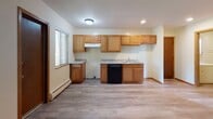 This single-floor unit offers a practical and cohesive layout designed for comfortable everyday living. The kitchen serves as a central feature, outfitted with warm-toned oak cabinetry both above and below the counters, granite-look laminate countertops, a double stainless steel sink, and a black dishwasher. A range hood is positioned above the cooking area, and light wood-look vinyl plank flooring runs throughout, lending a clean, consistent aesthetic across the space.

The open living area is generously proportioned, with multiple windows allowing natural light to fill the room. A wall-mounted air conditioning unit and baseboard heating provide year-round climate control. The neutral cream-toned walls create a bright, versatile backdrop throughout.

The bedrooms are quiet and well-sized, each featuring the same vinyl plank flooring, baseboard heating, and ample natural light through standard windows with blinds. The spaces are simple and functional, well-suited for furnishing to individual needs.

The bathroom is clean and straightforward, featuring a full tub-shower combination with built-in shelving, a white vanity with storage below, a toilet, and matching wood-look flooring that ties the space together with the rest of the unit.