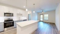 Located at 50 Lago Mar Way in Jacksonville, FL, this single-story, 3-bedroom, 1-bathroom residence offers a bright and modern living experience. The open-concept kitchen and living area serves as the heart of the home, featuring luxury vinyl plank flooring, recessed lighting, and a ceiling fan. The kitchen is well-equipped with stainless steel appliances—including a side-by-side refrigerator, range, and microwave—two-tone cabinetry with white upper cabinets and gray lower cabinets, a white quartz countertop island with pendant lighting, and a clean white subway tile backsplash. The living area extends naturally from the kitchen, benefiting from natural light through large windows and a glass door leading to an outdoor balcony with outdoor views. Each bedroom features plush carpet flooring, a ceiling fan, and natural light from windows. The spacious primary bedroom offers direct access to the bathroom, which includes a soaking tub/shower combination and white vanity cabinetry. Two walk-in closets with wire shelving provide ample storage. A dedicated laundry area houses a full-size washer and dryer. This residence combines clean, contemporary design with functional living spaces throughout.