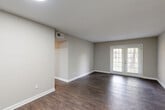 Located at 1606 Pinecroft Rd in Greensboro, NC, this single-story 2-bedroom, 1-bathroom home offers a practical and well-organized layout across a comfortable footprint. The living room serves as the centerpiece of the home, featuring rich dark hardwood-style flooring, neutral gray walls, clean white baseboards, and a standout set of French doors that invite natural light and provide views of the surrounding greenery outside. The kitchen is efficiently designed and equipped with stainless steel appliances including a gas range, over-the-range microwave, and full-size refrigerator, complemented by white shaker-style cabinetry, a white countertop, and a single-basin sink — all set atop matching dark hardwood-style floors. Both bedrooms offer plush carpet flooring and neutral tones, creating a calm and comfortable atmosphere. The spacious primary bedroom includes a generous walk-in closet outfitted with wire shelving, while the second bedroom features its own closet with built-in shelving. A hallway connects the bedrooms to the full bathroom, which includes a tub-shower combination. Two dedicated closets provide additional storage throughout the home, rounding out a functional and well-appointed living space.