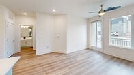 Located at 523 N Spring St in Greensboro, NC, this well-appointed 2-bedroom, 2-bathroom residence offers a thoughtfully designed single-floor layout. The open-concept living, dining, and kitchen area serves as the heart of the home, where light hardwood-style flooring, crisp white walls, and a ceiling fan create a bright, airy atmosphere. A glass-paneled door connects the living area to a private balcony, inviting natural light throughout.

The kitchen is a standout feature, showcasing white shaker cabinetry, a grey subway tile backsplash, quartz countertops, and a center island with a built-in sink and pendant lighting overhead. Stainless steel appliances—including a refrigerator, range, and microwave—complete the space, while an adjacent pantry provides additional storage.

Both bedrooms are generously sized with large windows and continue the hardwood-style flooring. The primary bedroom includes an en suite bathroom with a glass-enclosed shower accented by marble-look tile, a white vanity, and direct access to a walk-in closet with wire shelving. The second bathroom features a tub-shower combination with matching marble-style tile surround. A dedicated laundry area and multiple closets round out this functional and modern home.