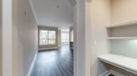This contemporary apartment at Lenox Farms offers a spacious 1020 square feet of living area on a single floor. The unit boasts two bedrooms, including a primary bedroom of 170 square feet, and two full bathrooms. The open-concept design creates a seamless flow between the living spaces, enhanced by neutral gray walls and pristine white trim throughout.

The living area is illuminated by large windows, providing abundant natural light and views of the surrounding community. Arched doorways add architectural interest, while crown molding lends a touch of elegance. The kitchen features modern stainless steel appliances, white cabinetry, and subway tile backsplash, creating a sleek and functional cooking space.

Both bathrooms are well-appointed with modern fixtures, including a vanity with ample storage in one and a stylish tub-shower combination in the other. The bedrooms are generously sized, with the primary bedroom featuring a ceiling fan for added comfort.

Throughout the apartment, durable wood-look flooring in a warm gray tone unifies the space and adds a contemporary feel. The unit also includes three hallways for easy navigation between rooms. Outside, residents can enjoy the well-maintained grounds of the Lenox Farms community, visible from the apartment's windows.

This turnkey apartment combines modern amenities with a practical layout, making it an ideal home for those seeking comfort and style in a convenient community setting.