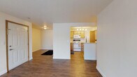 Located at 210 South Farr Road in Spokane, Washington, this single-floor unit offers a practical and well-organized layout designed for comfortable everyday living. The open-concept living and dining area is finished with warm hardwood-style flooring that flows throughout the main living spaces, creating a cohesive and inviting atmosphere. A sliding glass door in the living room fills the space with natural light and provides direct access to the exterior.

The kitchen is efficiently designed with warm oak cabinetry, light countertops, a full suite of white appliances including a range, microwave, and refrigerator, and a peninsula with bar seating — ideal for casual dining. The kitchen connects seamlessly to the living area, enhancing the open feel of the home.

The bedrooms are carpeted for comfort and feature windows that bring in natural light and outdoor views of the surrounding greenery. The bathroom is finished with oak cabinetry, a vanity with mirror, and hardwood-style flooring consistent with the rest of the unit.

Overall, the space presents a clean, neutral palette with functional finishes throughout, offering a straightforward and livable environment in a convenient Spokane location.