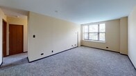 Located at 1380 E Hyde Park Blvd in Chicago's historic Hyde Park neighborhood, this single-floor unit offers a practical and comfortable layout designed for everyday living. The spacious living area is finished with neutral-toned carpet and light-colored walls, creating a clean and inviting atmosphere. A dedicated entry leads directly into the main living space, which connects seamlessly to the kitchen.

The kitchen is equipped with dark wood cabinetry, granite-style countertops, a tile floor, and white appliances including a coil-burner electric range and an over-the-range microwave, offering a fully functional cooking space.

The unit features multiple carpeted bedrooms, each finished with the same warm, neutral palette. The larger bedroom benefits from a corner window configuration, flooding the room with natural light and offering views of the surrounding greenery. Additional bedrooms are well-proportioned with individual windows providing natural light.

The full bathroom is neatly finished with a dark wood vanity, a light composite countertop, a large framed mirror, and a tub-shower combination with clean white tile surround. Chrome fixtures and coordinating hardware complete the space. Overall, the unit provides a functional, move-in-ready living environment in one of Chicago's most culturally vibrant neighborhoods.