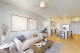 Located in the Astir community of Miami, FL, this well-appointed one-bedroom, one-bathroom residence offers a thoughtfully designed open-concept layout with light wood-style flooring throughout, creating a warm and cohesive aesthetic from room to room.

The living room is bright and welcoming, featuring a ceiling fan, soft neutral walls, and a large window dressed with floor-length drapes that invite natural light while offering a view of the surrounding neighborhood. The space flows seamlessly into the kitchen, which is a standout feature of the home. Outfitted with flat-front cabinetry in crisp white and light wood tones, stainless steel appliances — including a full-size refrigerator, range, microwave, and dishwasher — and a generous white quartz island with bar seating, the kitchen is both functional and visually striking. Recessed lighting and open shelving complete the modern look.

The bedroom is a calm retreat with a bold accent wall, ceiling fan, and a window with outdoor views, offering a comfortable and private atmosphere. The dedicated closet provides practical storage. The bathroom features a clean, modern vanity with ample drawer space and a full tub-shower combination with white tile surround. An in-unit laundry area and a private balcony round out the functional highlights of this well-designed residence.