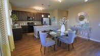 This two-floor residence offers a thoughtfully designed layout that blends modern aesthetics with functional living. The open-concept main living area seamlessly connects the kitchen and dining space, creating an inviting atmosphere ideal for both everyday living and entertaining.

The kitchen is appointed with rich, dark cabinetry, a subway tile backsplash, and stainless steel appliances, including a French door refrigerator and a range. A central island with a built-in sink provides additional prep space and features bar seating, making it a natural gathering point. Pendant lighting hangs above the island, complementing the recessed track lighting overhead.

The adjacent dining area is anchored by warm, dark hardwood flooring that runs throughout the main level, adding depth and character to the space. The open layout allows for generous dining furniture, with ample room to move freely between areas. Neutral wall tones provide a versatile backdrop that pairs well with a variety of décor styles.

The two-floor configuration offers a clear separation between common living spaces and private areas, providing both openness and privacy. Overall, the space presents a cohesive, contemporary design with quality finishes and a warm, welcoming ambiance.