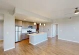 Located at 3065 Champion Ring Rd in Fort Myers, FL, this well-appointed 3-bedroom, 2-bathroom single-story home offers a thoughtfully designed open-concept layout. The combined kitchen and living area serves as the heart of the home, showcasing a large central island with a white quartz countertop, undermount sink, and stylish pendant lighting. The kitchen is outfitted with sleek taupe cabinetry, a white subway tile backsplash, and a full suite of stainless steel appliances. Warm wood-look flooring flows seamlessly throughout the entire home, lending a cohesive and contemporary feel. The living area opens to a private balcony through a glass-paneled door, allowing natural light to fill the space. Each of the three bedrooms features neutral wall tones, wood-look flooring, and windows with blinds that frame outdoor views. The primary bedroom offers a generous footprint with dedicated closet space. Both bathrooms are finished with modern vanities, quartz countertops, large-format mirrors, and clean matte black hardware accents. A dedicated laundry room houses a full-size washer and dryer with built-in shelving above. Three closets and a hallway complete the functional floor plan of this move-in-ready Fort Myers home.