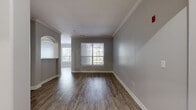 Located at 517 Lowell St in Andover, MA, this single-story residence offers 1,110 square feet of thoughtfully designed living space across 3 bedrooms and 2 bathrooms. The open-concept living room features wood-look flooring, crown molding, large windows that invite abundant natural light, and a distinctive arched passageway connecting to the kitchen. The galley-style kitchen is well-appointed with dark espresso cabinetry, granite countertops, a subway tile backsplash, stainless steel appliances including a refrigerator, range, microwave, and dishwasher, and an in-unit washer visible through the rear hallway. Both bathrooms are finished with multi-tone slate stone tile flooring, dark wood vanities, granite countertops, and framed mirrors. The full bath includes a tiled tub-shower combination with an arched alcove accent. The 150-square-foot primary bedroom features plush carpeting, a ceiling fan, and a walk-in closet with wire shelving. The additional bedrooms are carpeted and include ceiling fans and windows with outdoor views. Three hallways connect the layout efficiently, complemented by a dedicated closet for additional storage throughout this well-finished Andover home.