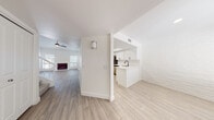 This two-floor space showcases a clean, modern aesthetic built around a consistent palette of crisp white tones and light wood-style flooring that runs throughout. A defining architectural feature is the white-painted brick that appears across multiple rooms, lending texture and character while maintaining a bright, cohesive look.

The open main level connects a living area — complete with a fireplace and ceiling fan — to a well-appointed kitchen. The kitchen features white shaker-style cabinetry with matte black hardware, white quartz countertops, a undermount sink, and stainless steel appliances including a range with over-the-range microwave. The layout promotes easy flow between living and cooking spaces.

The bedrooms continue the white brick motif, with natural light entering through blinded windows. Vaulted ceilings in certain rooms add a sense of openness, and closets with bifold doors provide built-in storage. One bedroom benefits from a ceiling fan and multiple windows, enhancing ventilation and light.

Bathrooms are updated with white vanities, quartz countertops, brushed gold and brushed nickel fixtures, large mirrors, and tub-shower combinations. The second bathroom features an elongated vanity with dual sinks. Light wood-tone flooring ties the bathrooms seamlessly to the rest of the space.