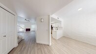 This two-floor space showcases a clean, modern aesthetic built around a consistent palette of crisp white tones and light wood-style flooring that runs throughout. A defining architectural feature is the white-painted brick that appears across multiple rooms, lending texture and character while maintaining a bright, cohesive look.

The open main level connects a living area — complete with a fireplace and ceiling fan — to a well-appointed kitchen. The kitchen features white shaker-style cabinetry with matte black hardware, white quartz countertops, a undermount sink, and stainless steel appliances including a range with over-the-range microwave. The layout promotes easy flow between living and cooking spaces.

The bedrooms continue the white brick motif, with natural light entering through blinded windows. Vaulted ceilings in certain rooms add a sense of openness, and closets with bifold doors provide built-in storage. One bedroom benefits from a ceiling fan and multiple windows, enhancing ventilation and light.

Bathrooms are updated with white vanities, quartz countertops, brushed gold and brushed nickel fixtures, large mirrors, and tub-shower combinations. The second bathroom features an elongated vanity with dual sinks. Light wood-tone flooring ties the bathrooms seamlessly to the rest of the space.