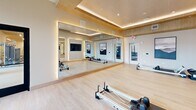 Located at 5810 Stax St NW in Huntsville, Alabama, this single-floor fitness center offers a generously sized, thoughtfully designed exercise facility. The space is defined by its warm wood-paneled ceilings, recessed and linear LED lighting, and a light neutral color palette that creates a clean, modern, and energizing atmosphere throughout.

The main exercise floor is expansive and open, accommodating a comprehensive array of cardio equipment — including treadmills, ellipticals, stationary bikes, and stair climbers — alongside a robust selection of strength-training machines, cable systems, free weights, and benches. Full-length wall mirrors amplify the sense of space, while built-in water fountains provide convenient hydration access.

A dedicated studio room offers a distinct environment for mind-body training, outfitted with Pilates reformers, stability balls, and resistance equipment. Ambient cove lighting frames a coffered wood-accented ceiling, and floor-to-ceiling mirrors line the walls, enhancing the room's bright, airy feel.

Large sliding glass doors and expansive windows throughout the facility connect the interior to an outdoor courtyard, flooding the space with natural light and providing views of the surrounding greenery. The combination of premium finishes, abundant equipment, and thoughtful layout makes this fitness center a well-appointed destination for a full range of exercise activities.