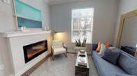 Located at 1221 E Broadway in Louisville's historic Highlands neighborhood, this thoughtfully designed single-floor residence offers a refined blend of modern finishes and comfortable living. The living room serves as a welcoming focal point, anchored by a sleek linear electric fireplace set beneath crown molding and framed by large, light-filtering windows. A curated mix of contemporary furnishings, warm accent lighting, and decorative greenery create an inviting, polished ambiance throughout.

The kitchen is equipped with white shaker cabinetry, dark granite countertops, a classic subway tile backsplash, and a full suite of stainless steel appliances, including a gas range, refrigerator, built-in microwave, and dishwasher. Wood-look flooring ties the space together seamlessly.

The primary bedroom is generously proportioned, featuring plush carpet, multiple windows that draw in natural light, and a ceiling fan for year-round comfort. It connects to a well-designed en-suite bath and a dedicated walk-in closet with built-in shelving and rod storage. A full-length mirror and granite-topped vanity with white cabinetry complete the suite. A second bedroom provides additional versatile living space, also with ample natural light and easy hallway access.