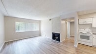 This single-floor home offers a thoughtfully arranged layout comprising four bedrooms, one bathroom, a combined kitchen and living room, and a hallway connecting the spaces. The living room serves as the centerpiece of the home, highlighted by a striking white brick fireplace with a dark hearth surround. Light hardwood-style flooring runs throughout, complementing the neutral, warm-toned walls and textured ceilings. Large windows fitted with vertical blinds allow ample natural light to fill the living areas, providing views of surrounding greenery.

The kitchen is well-equipped and features white shaker-style cabinetry extending to the ceiling, granite countertops, a subway tile backsplash, a stainless steel sink, and white appliances including a range and dishwasher. An in-unit washer is also integrated within the kitchen area, adding everyday convenience.

Each of the four bedrooms is finished with the same light hardwood-style flooring and neutral tones, with windows bringing in natural light. The primary bedroom offers a comfortable and functional footprint. The bathroom is clean and practical, appointed with a tub-shower combo, white tile surround, granite vanity countertop, and white cabinetry, maintaining the consistent, fresh aesthetic found throughout the home.