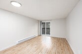 This single-floor unit offers a clean, functional layout designed for comfortable everyday living. The open-concept living and dining area is finished with light wood-style flooring that extends throughout the main living space, creating a bright and cohesive feel. A sliding glass door leads directly to a private balcony, allowing natural light to fill the room and offering pleasant views of surrounding greenery.

The kitchen is designed as a galley-style space, featuring dark wood-tone cabinetry, white countertops, and stainless steel appliances including a refrigerator, electric range, over-the-range microwave, and dishwasher. A skylight overhead adds additional natural light to the kitchen. A peninsula counter with seating potential connects the kitchen to the main living area, enhancing the open flow of the space.

The bedroom is a generously sized, carpeted room with a window that brings in natural light and overlooks greenery outside. A baseboard heating unit ensures year-round comfort. The bathroom includes a full soaker tub and shower combination with smooth wall surrounds and chrome fixtures. Throughout the unit, textured ceilings, neutral wall tones, and recessed and flush-mount lighting contribute to a clean, understated aesthetic that is both practical and inviting.