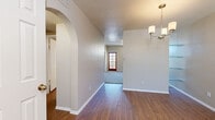 Located in Phoenix, AZ, this single-story, 2-bedroom, 2-bathroom home offers a well-organized layout with a living room, dining room, kitchen, and hallway connecting two dedicated closets. The interior opens with a distinctive arched entryway framed by wood-look flooring that flows through the main living and dining areas. The living room is a standout space, featuring vaulted ceilings, a large arched window that fills the room with natural light, a ceiling fan, and a tiled fireplace with glass doors—adding warmth and character. The kitchen is equipped with warm-toned wood cabinetry, light countertops, tile flooring, and stainless steel appliances including a range, microwave, and dishwasher, plus a window view of the outdoors. The primary bedroom offers generous proportions with plush carpeting, a ceiling fan, and a large arched window. The second bedroom features hardwood-style flooring and an outdoor-facing window for natural light. Both bathrooms include a tub-shower combination. One bathroom features wood-look flooring and a vanity with wood cabinetry, while the other is finished with classic white fixtures. The textured ceilings and neutral wall tones throughout contribute to a clean, cohesive aesthetic.