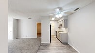 Located at 100 Bent Tree Dr in Daytona Beach, Florida, this single-floor residence offers a practical and well-organized layout with two bedrooms and two bathrooms. The open living and dining area features plush carpeting, a ceiling fan with light fixture, and a textured ceiling, creating a comfortable, casual atmosphere. The space flows naturally into the kitchen, which is finished with grey shaker-style cabinetry, light stone countertops, wood-look vinyl flooring, and black appliances including a refrigerator and dishwasher. A pantry provides additional storage convenience.

Both bedrooms are carpeted and equipped with ceiling fans. The primary bedroom is generously sized, featuring two windows with vertical blinds that invite natural light and views of the surrounding greenery. Each bedroom includes dedicated closet space, with multiple closets spread throughout the unit offering excellent overall storage. The second bedroom also benefits from natural light via a window with vertical blinds.

Both bathrooms are finished with wood-look vinyl flooring, grey vanity cabinetry, white countertops, and tub/shower combinations. The clean, neutral color palette throughout the home creates a bright and move-in-ready feel well-suited for comfortable Florida living.