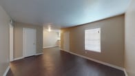Located at 9400 Bauman Rd in Houston, Texas, this single-story unit offers a practical and well-organized layout throughout. The main living area features dark hardwood-style flooring that extends through the entry and common spaces, complemented by neutral beige walls and white baseboards that create a clean, consistent aesthetic. Natural light filters in through blinds-covered windows, lending a bright and open feel to the living space. The front entry door is equipped with multiple locks, providing added security.

The bedrooms are carpeted for comfort, each outfitted with ceiling fans and light fixtures to promote air circulation. Windows with blinds allow natural light while maintaining privacy. One bedroom includes direct access to a hallway, adding to the functional flow of the floor plan.

The bathroom features a wide vanity with a speckled countertop, white cabinetry, a large mirror with overhead lighting, and a full tub-shower combination, offering a clean and utilitarian design. The kitchen is equipped with white cabinetry, speckled countertops, an electric coil range, and an overhead ventilation hood, providing all essential cooking amenities. The textured ceilings are consistent throughout the unit, adding subtle architectural detail to the overall interior.
